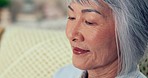 Senior woman, Asian face and reading closeup at retirement home feeling relax and calm on sofa. Living room, elderly female person and weekend with peace in a house on a lounge couch with wrinkles