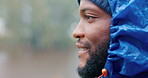 Profile, space and a black man hiking in the rain, outdoor in nature for travel, tourism or adventure. Face, thinking and winter with a happy young hiker in a forest or woods for freedom and vacation