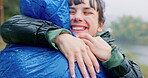 Hiking, travel and a couple hugging in the rain while outdoor in nature together for romance or adventure. Smile, freedom or love with a man and woman bonding while camping in wet winter weather