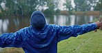 Rain, man and hiking, stretching arms on morning adventure with peace, calm and nature travel. Relax, freedom and happy person camping at lake for holiday in woods with winter weather, water and fun.