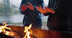 Hands, warm and friends with fire on camping adventure, trip or outdoor for a bonfire in the woods, forest or countryside. Campfire, flame and men relax together on winter vacation in nature