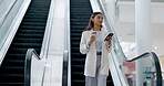 Phone, coffee and a business woman on an escalator in an office building for corporate or professional work. Mobile, walking and a young female employee reading a text message for communication