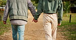 Back of couple, holding hands and walking on path in garden for love, care and relax on romantic date together in nature. Closeup of man, woman and stroll in park for freedom, quality time or loyalty