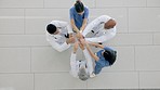 Top view, hands together and doctors with motivation, support and trust in a hospital, teamwork and collaboration. Group, staff and medical professionals with team building, clinic mission and goals