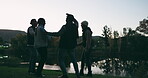 Night, high five and friends in celebration while camping happy for party by the lake together in forest or the woods. Winning, success and silhouette of excited group of people on vacation in sunset