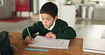 Boy, writing and education with thinking, home or pencil for problem, development or learning course. Male child, school notebook and studying at desk for assessment, test or homework in family house