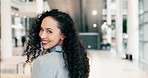 Happy, confidence and face of a businesswoman in the office walking with healthy, long and curly hair. Happiness, smile and portrait of a young professional female person in the modern workplace.