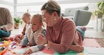 Mom, dad and helping children with drawing on floor for bonding, teaching and learning together. Color, paper and father, mother and kids in creative play in development, quality time and family home