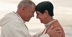 Old couple, forehead touch and hug while at beach, happiness and retirement together, travel and outdoor. Communication, happy people and pension with holiday, marriage and commitment with sunset