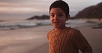 Face, sunset and boy with happiness, beach and travel with joy, seaside holiday and playful. Portrait, male child and kid on seaside vacation, smile and youth with weekend break, adventure or freedom