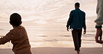 Throwing sand, playful and a child at the beach with family for a vacation at the ocean in sunset. Happy, playing and a little boy or kid with a ball in the water or sea and father on a holiday