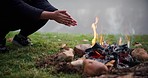 Bonfire, wood and camping with warm hands, heat and relax in nature, grass and rocks for safety at bbq. Fire, flames and burning for charcoal, barbecue and person for adventure, camp and survival