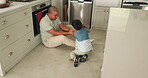 Kitchen, games and a father playing with his son in their home for family bonding or time together. Smile, playful and a happy boy child having fun with his dad while sitting on the floor of a house