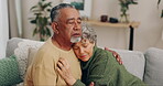 Senior couple, love and hug for empathy and comfort or security on home sofa. Elderly man and sad woman embrace and together in living room for care, compassion and support or sympathy in retirement