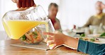 Family, lunch and hands pour juice for child at dinner table for meal, eating together or breakfast. Health, brunch and closeup of fruit drink in glass for parents, grandparents and children at home