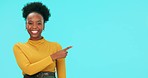 Black woman, face and pointing to mockup with a smile in studio isolated on a blue background. Portrait, copy space or person with hand for advertising, marketing or commercial promotion for branding