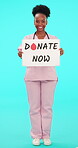 Poster, blood and donation with a nurse black woman on blue background in studio for healthcare. Portrait, medical and volunteer with a happy young female medicine professional holding a sign