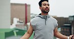Asian man, fitness and skipping rope on rooftop in city for workout, cardio exercise or outdoor training. Fit, active and sport male person jumping with ropes for healthy body wellness in urban town