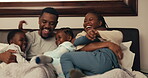 Black family, children and funny with parents in bed for playing or laughing in the morning together. Mother, father and kids in the bedroom for love, comedy or bonding while in their home to relax