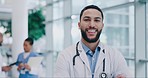 Crossed arms, happy and face of a man doctor standing in the medical hospital with confidence. Smile, professional and portrait of mature male healthcare worker from Colombia in a medicare clinic.