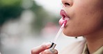 Lipstick, closeup and a woman with makeup in the city for fashion, skincare or facial care. Hand, mouth and a girl or person with a cosmetics applicator for wellness, color and shine from lipgloss