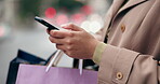 Woman, phone and hands with shopping bag in city street for online communication, networking or social media. Closeup of female person or shopper typing on mobile smartphone app on sidewalk in travel