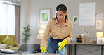 Woman, cleaning and wipe desk with chemical detergent, housekeeping and disinfectant for furniture. Cleaner, hygiene and scrub dust from surface with house work, liquid soap in bottle and gloves