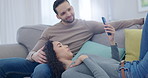 Couple, talking and phone on relax sofa for blog reading, social media and online information in home living room. Happy man, woman and technology app for romantic break research, internet or bonding