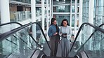 Escalator, office and business women on tablet on commute, travel and arrival at work. Modern building, professional team and female people talking on electric stairs for discussion, project and job