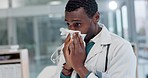 Allergy, flu and sick doctor blowing nose while working in office on a laptop with viral infection. Sneezing, tissue and African guy health expert with virus, infection and bacteria, covid or burnout