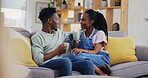 Coffee, talking and a happy black couple on a sofa in the living room of their home together. Tea, love or smile, tea with a man and woman in conversation in their house while drinking a beverage