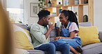 Tea, chatting and a happy black couple on a sofa in the living room of their home together. Coffee, love or smile with a man and woman in conversation in their house while drinking a beverage