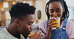 Happy, black couple and orange juice in home living room on sofa in healthy diet, nutrition or wellness. African man, woman and drink fruit in glass, organic vitamin c and funny vegan laugh together