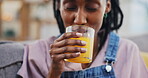 Happy, black woman and orange juice in home living room on sofa in healthy diet, nutrition and wellness. African person, smile and drink fruit glass in hydration, organic vitamin c or vegan benefits