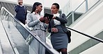 Escalator, tablet and business women in a building talking before corporate meeting or seminar. Conversation, digital technology and female lawyers speaking on moving stairs in airport or hotel lobby