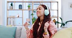 Dance, music and woman with headphones on a sofa listening to a playlist and album in the living room. Happy, smile and young female person moving and streaming a song or radio in the lounge at home.