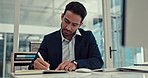 Businessman, writing and typing in finance, budget planning or schedule notes at the office. Asian man, accountant or financial advisor working on notebook and computer for reminder at the workplace