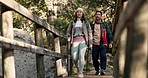 Hiking, bridge and couple outdoor on a forest path for exercise, workout and adventure. Walking, trekking and young people in nature in the woods for travel fitness journey together and talking