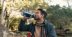 Man, hiking and drinking water from bottle in outdoor exercise, fitness or training in nature, woods or trekking in forest. Drink, liquid or relax on break in healthy cardio workout or adventure