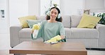 Housekeeping, headphones and woman cleaning the table with detergent, cloth and gloves at home. Female maid, cleaner or housewife dancing and wipe the furniture for dust, dirt or bacteria with music.