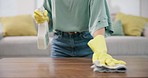 Housekeeping, closeup and woman cleaning the table with detergent, cloth and gloves in living room. Zoom of female maid, cleaner or housewife wipe furniture for dirt, dust or bacteria in an apartment