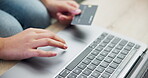 Person, laptop and hands with credit card in online shopping, payment or banking on living room desk at home. Closeup of shopper with debit and typing bank details on technology in ecommerce on table