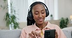 Headphones, phone and young woman on a sofa relaxing, dancing and listening to music or radio. Happy, technology and African female person streaming a playlist, song or album on a cellphone at home.