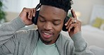 Man, headphones and smile on sofa for sound, radio and audio subscription. Face of african guy listening to calm music, podcast media and hearing jazz song with freedom for break on living room couch