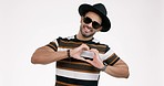 Fashion, hands in heart and man on a white background with trendy clothes, style and sunglasses. Happy, relax and portrait of isolated person with hand gesture, symbol and emoji for love in studio