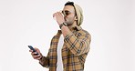 Phone, coffee and man on a white background in hipster outfit, style and trendy clothes in studio. Fashion, relax and isolated person drinking tea on smartphone for social media, internet and typing