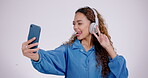 Woman, peace or headphones for selfie in studio, live streaming or video call on white background. Profile picture, happy gen z model and v sign with tongue out, blowing kiss or emoji on social media