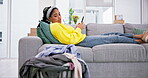 Lazy, phone and woman tired of laundry on a couch in a living room distracted by social media in a home. Housekeeping, annoyed and young person on a sofa with fatigue and bored of clothes in a house