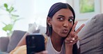 Peace sign, blow kiss and selfie of Indian woman on sofa take photo for social media, update and blog. Home, influencer and person with hand sign for profile picture, relax and video in living room