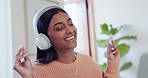 Dance, headphones and young woman in the living room listening to music, playlist or radio. Happy, smile and Indian female person moving and streaming an album or song on a sofa in the lounge at home